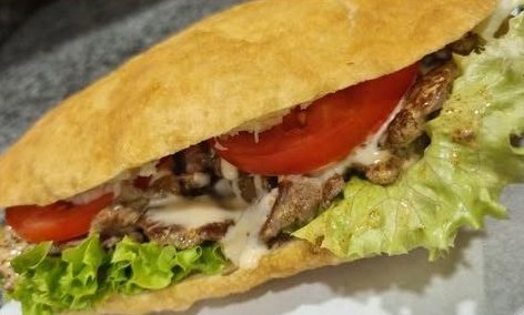 Bokit garni de poulet, salade, tomate et sauce blanche